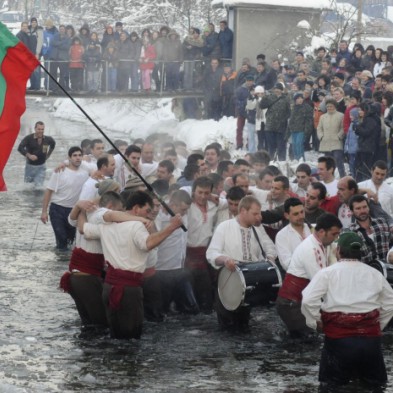 Мъже играят хоро и пеят народни песни в ледените води на река Тунджа