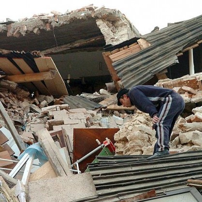 Мъж стои върху останките от къща недалеч от Акуила след земетресението в Италия