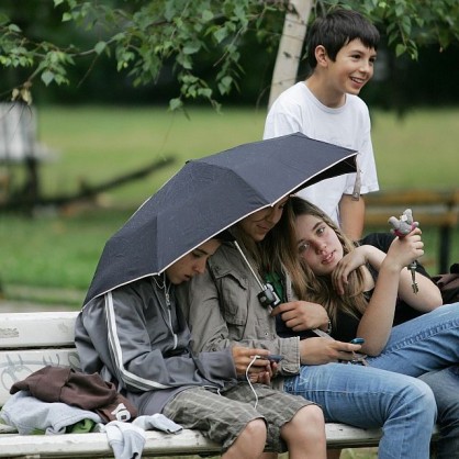 Няколко деца се крият от дъжда под общ чадър
