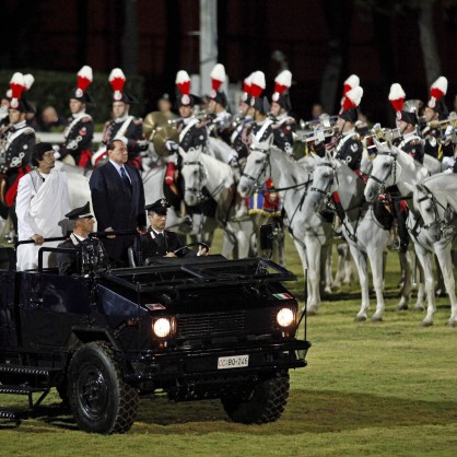 Либийският лидер Муамар Кадафи и италианският премиер Силвио Берлускони стоят в колата пред карабинери на кон