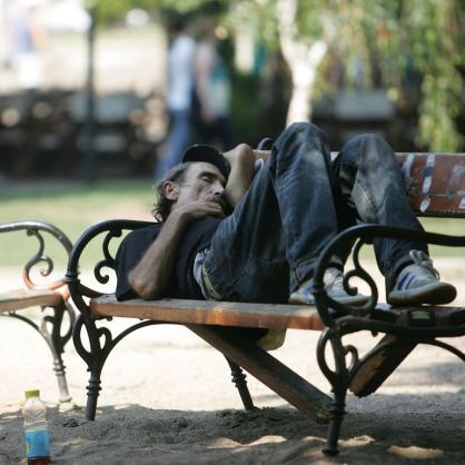 Мъж спи на пейка в парка в жегата