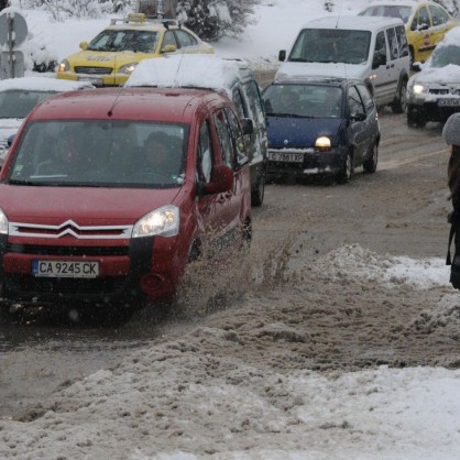 Пешеходец опитва да изгази през кишата - сняг в София