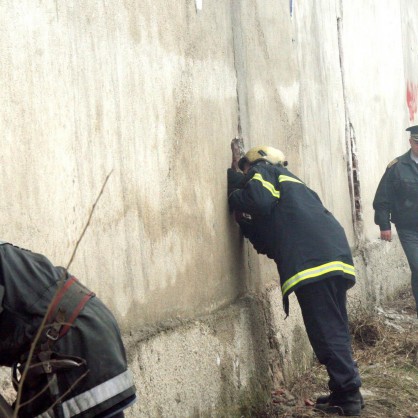 Огнеборци оглеждат през дупки в стената склада