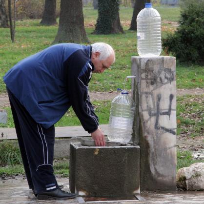 Мъж налива вода на градска чешма