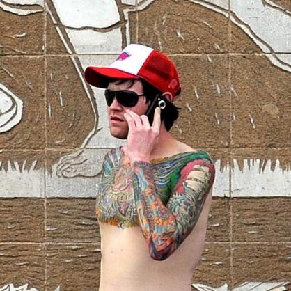 Мъж с татуировки говори по мобилен телефон