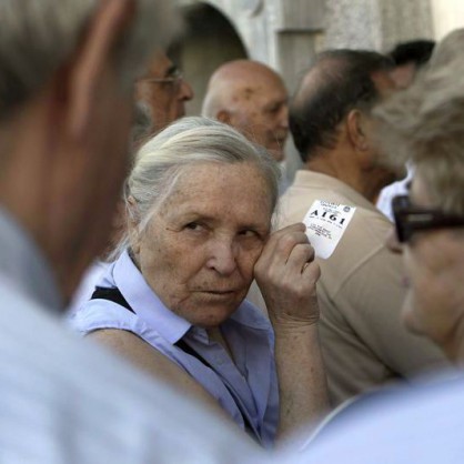 Възрастна жена държи талон за получаване на пенсия в Гърция