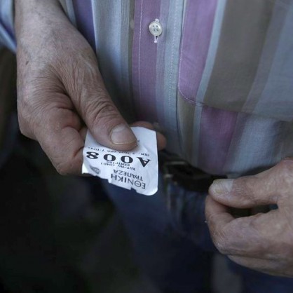 Възрастен мъж с талон за получаване на пенсия в Гърция