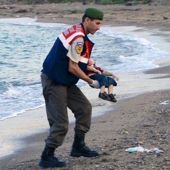 Полицай носи телцето на детето набежанци, изхвърлено на брега