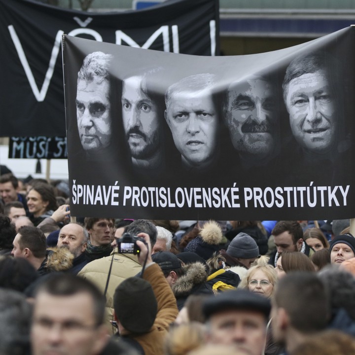 Протестиращи срещу убийството на журналиста държат плакат с портрети на министри с надпис ”Мръсни антисловашки проститутки””